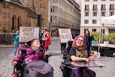 Aufführung der Theater-AG der Diakonie am Thonberg; man sieht zwei Menschen im Rollstuhl, die Schilder tragen "nehmt mich ernst!" und "Hört mir zu!" steht auf den Schildern.