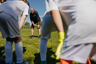 Ein Trainer schwört Teilnehmer*innen der Fußballschule aufs Training ein