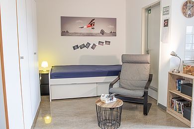 gemütliches Schlafzimmer im Internat, mit Schrank, Bett und Sessel