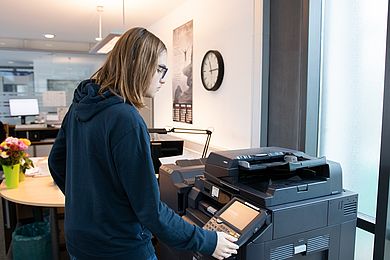 Auszubildender Am Lernort "Rezeption" bedient einen Drucker