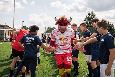 Maskottchen Bulli klatscht die Teilnehmenden der Fußballschule ab