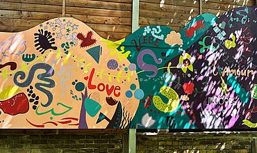 Wandbild, das im Rahmen des Projekts am Budde-Haus entstanden ist. Bunte Formen und Farben und der Schriftzug "Love", "Liebe" in verschiedenen Sprachen.