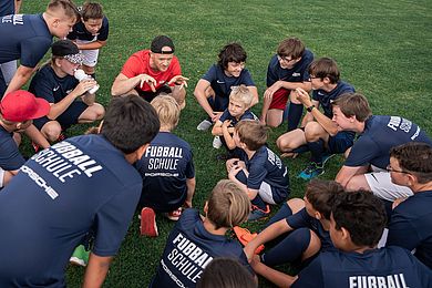 Trainer und Teilnehmende der RB Fußballschule bei einer Teambesprechung