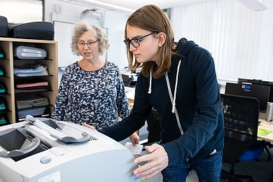 Ein Auszubildender und eine Ausbilderin an der Falzmaschine