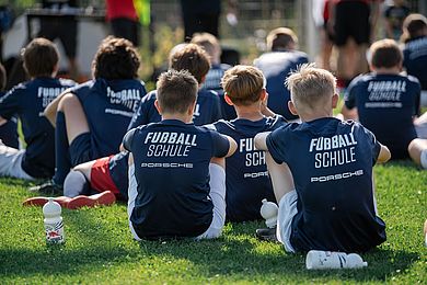 Teilnehmende der RB Fußballschule sitzen auf dem Fußballplatz