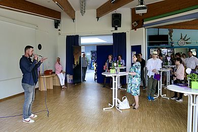 Sayes performt vor Teilnehmenden des Netzwerkdinners, die an weißen runden Stehtischen zuhören.