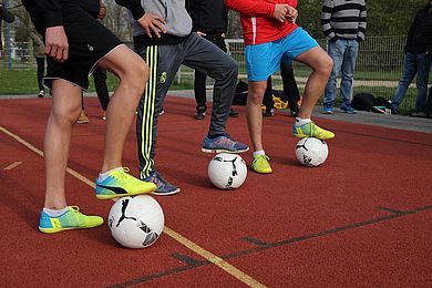 Drei Jugendliche beim Fußball, alle haben einen Fuß auf den Ball gestellt.