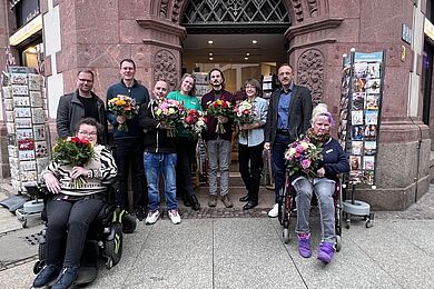 Gruppenbild der Mitarbeitenden vom Nikolai-Eck mit Blumensträußen vor dem Laden