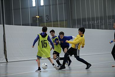 Einige Kinder rennen um den Fußball und versuchen, ihn an sich zu nehmen