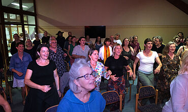 Das Foto zeigt mehrere in Reihe stehend und tanzende Personen