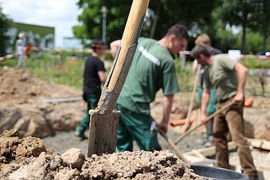 Teilnehmende im Fachbereich Gartenbau - Spaten im Vordergrund