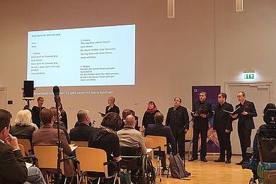 Das A capella Ensamble Thonkunst singt ein Lied, der Text wird an die Wand projiziert