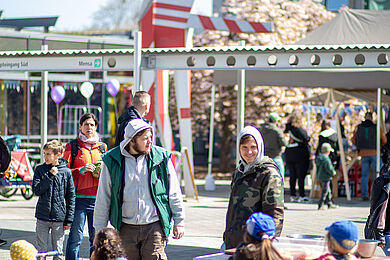 Blick auf den Hof zwischen Eingang des BBW und Mensa. Bei Sonnenschein halten sich dort viele Personen auf. Im Hintergrund sieht man Luftballons.